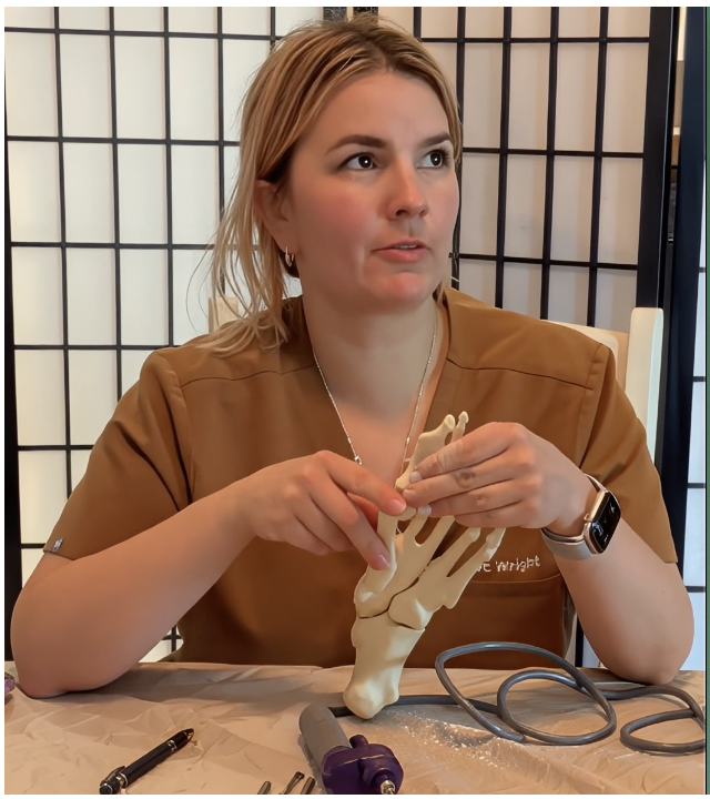 Dr. Kayla Wright, DPM, holding a foot and ankle anatomy model while explaining a treatment plan.
