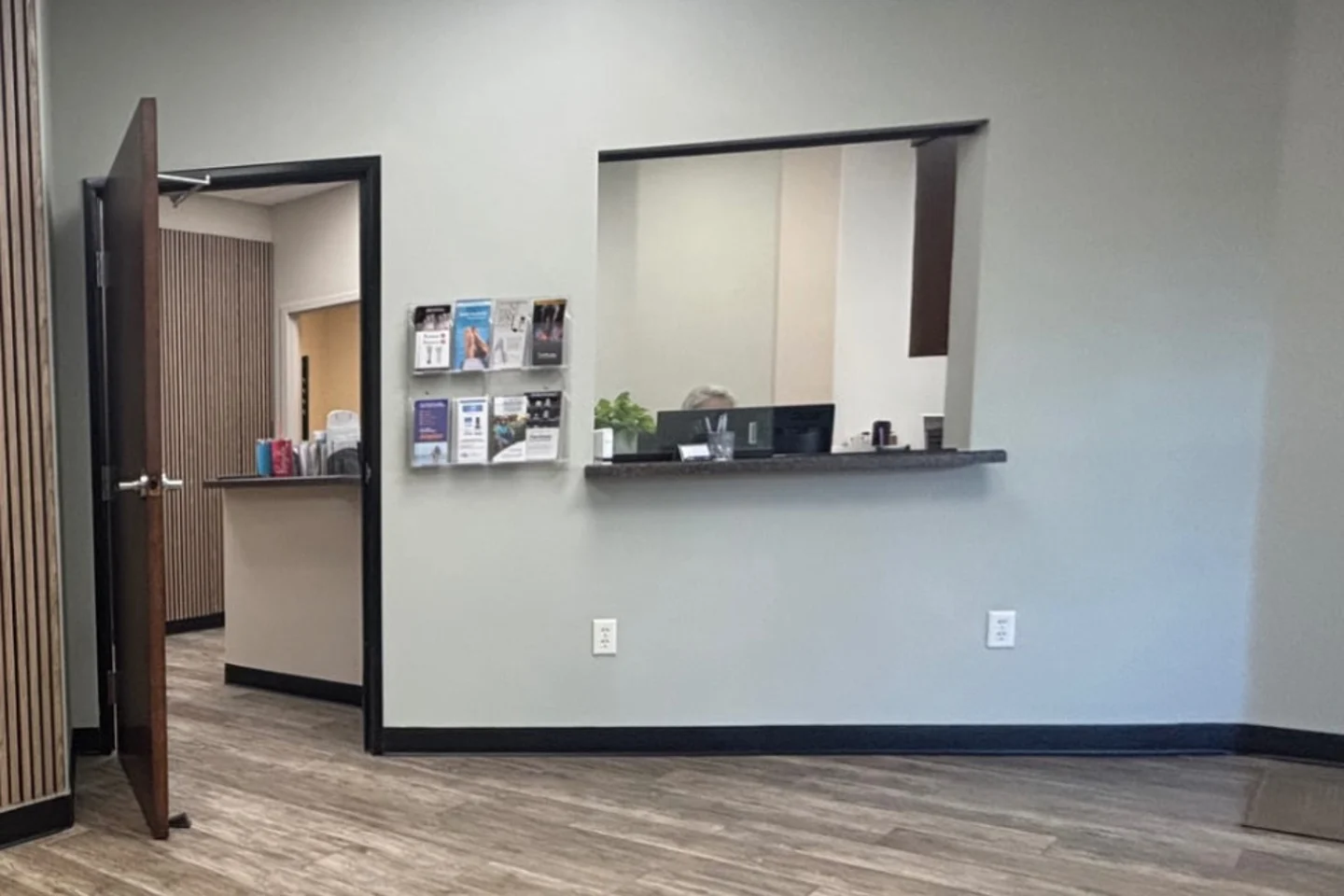 Metro Foot & Ankle reception and check-in window with wood slat wall detail and wood-look flooring